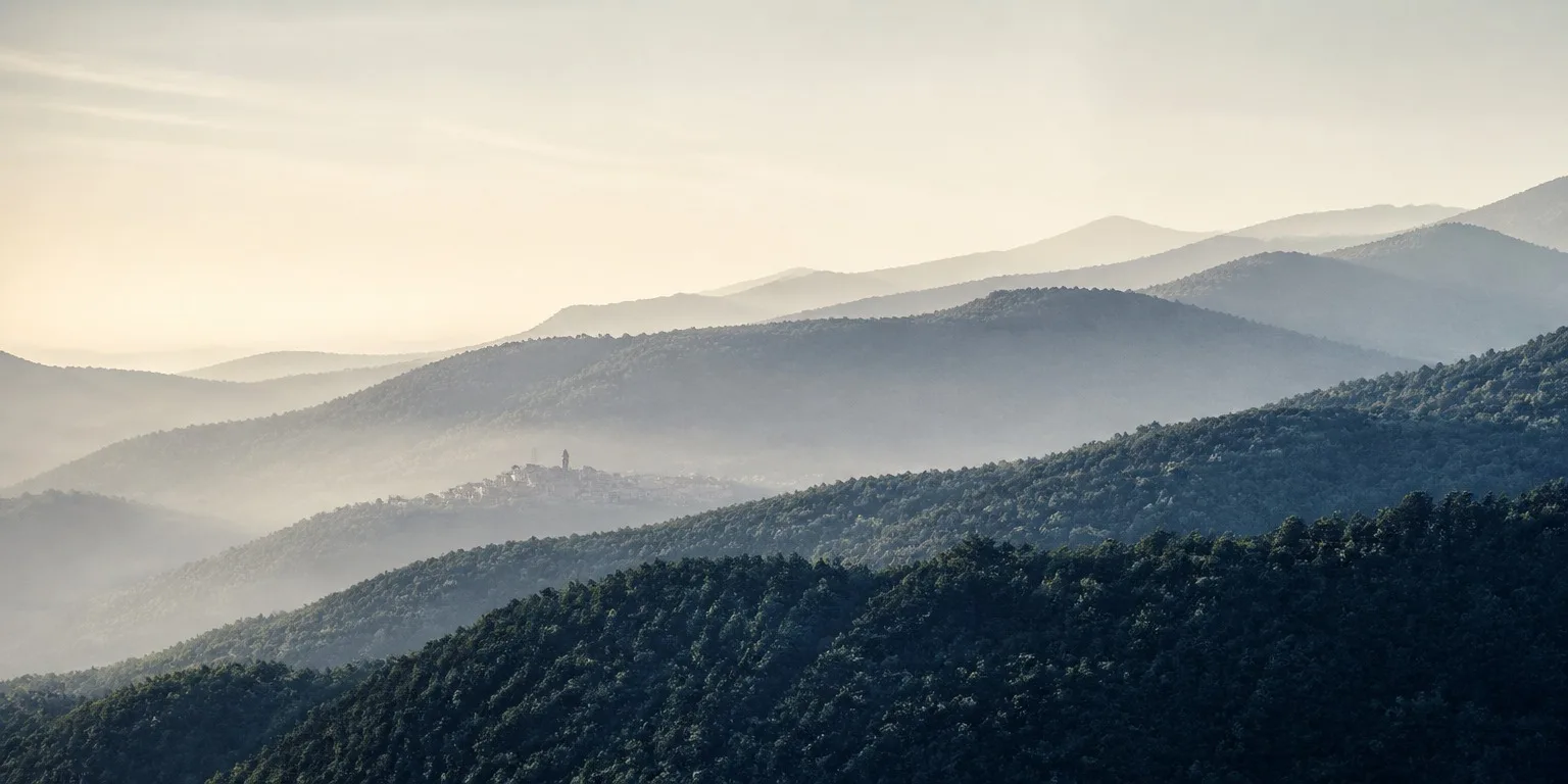 Les crêtes de la Montagne Noire dans la brume, un village et son clocher au fond de la vallée